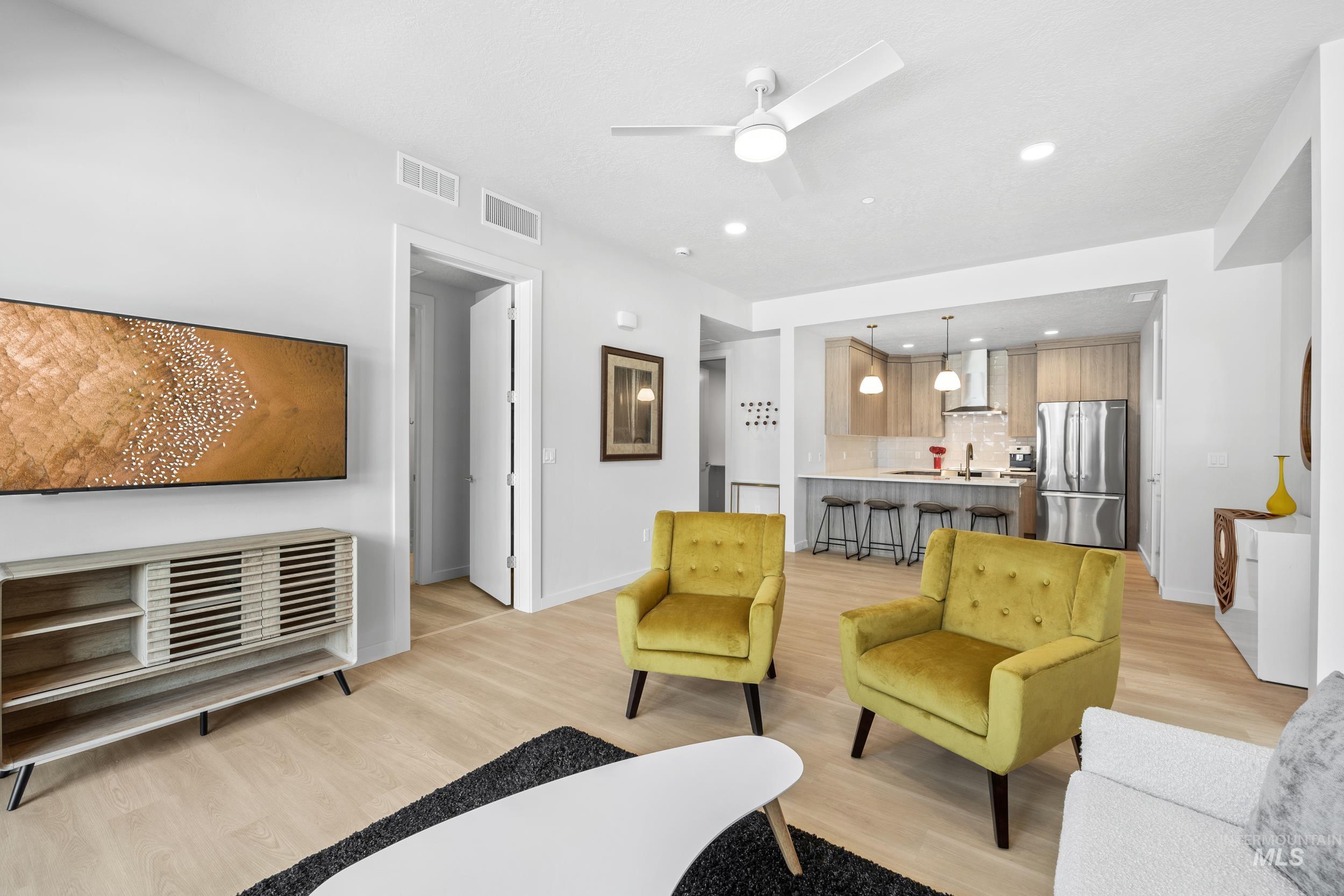 Living room with light wood-style flooring, ceiling fan, and recessed lighting