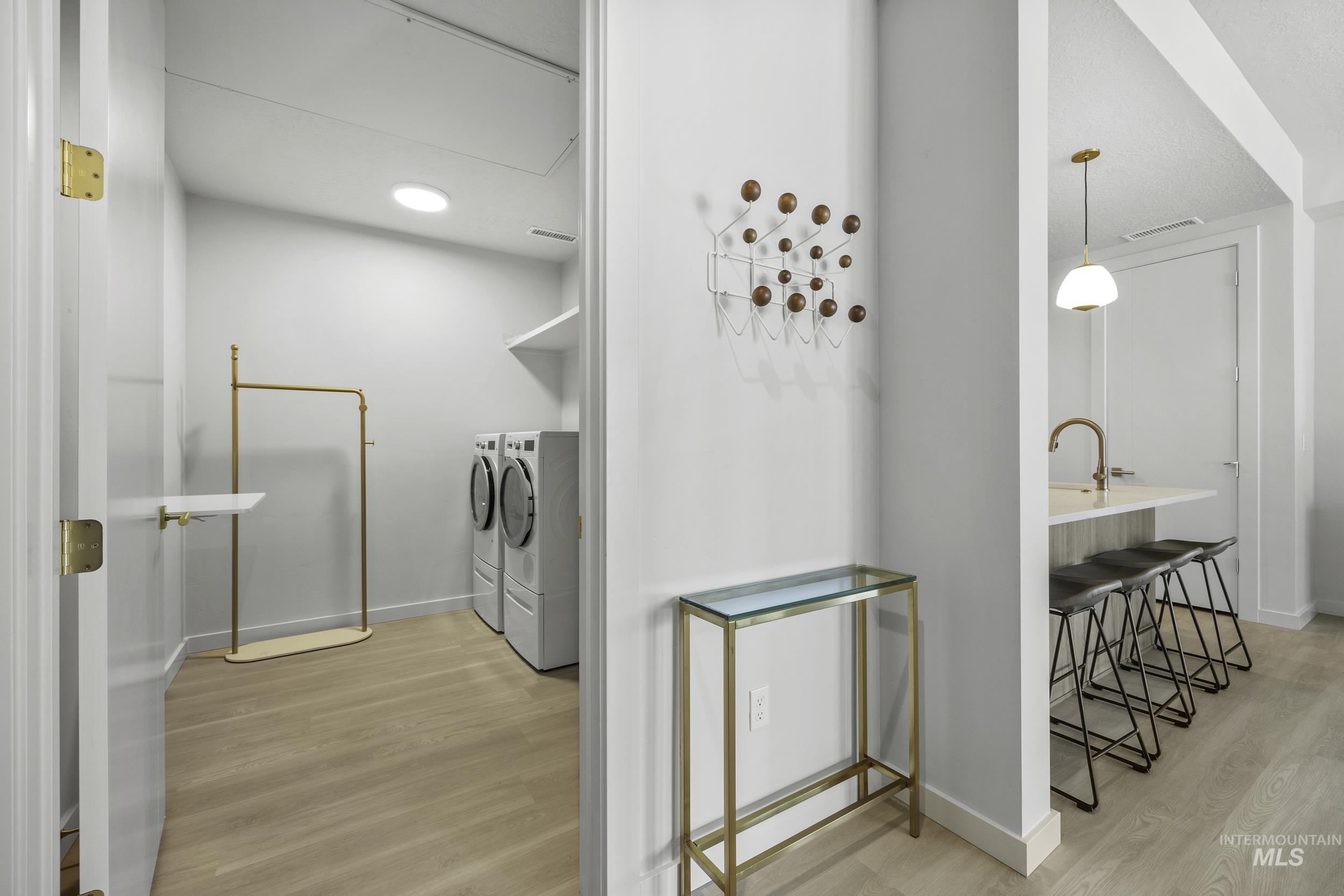 Washroom with washer and dryer and wood finished floors