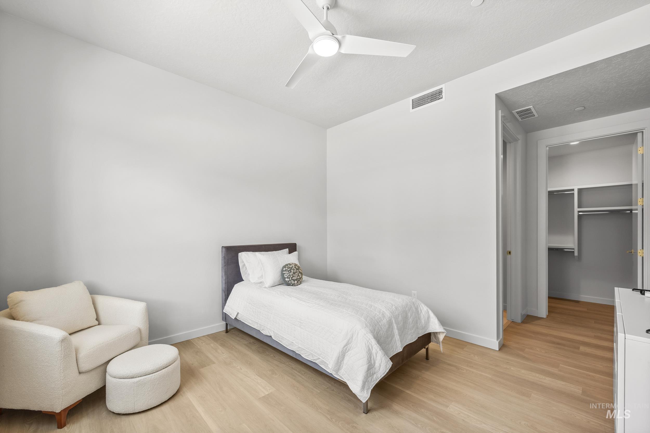 Bedroom with light wood-type flooring, a ceiling fan, and a spacious closet