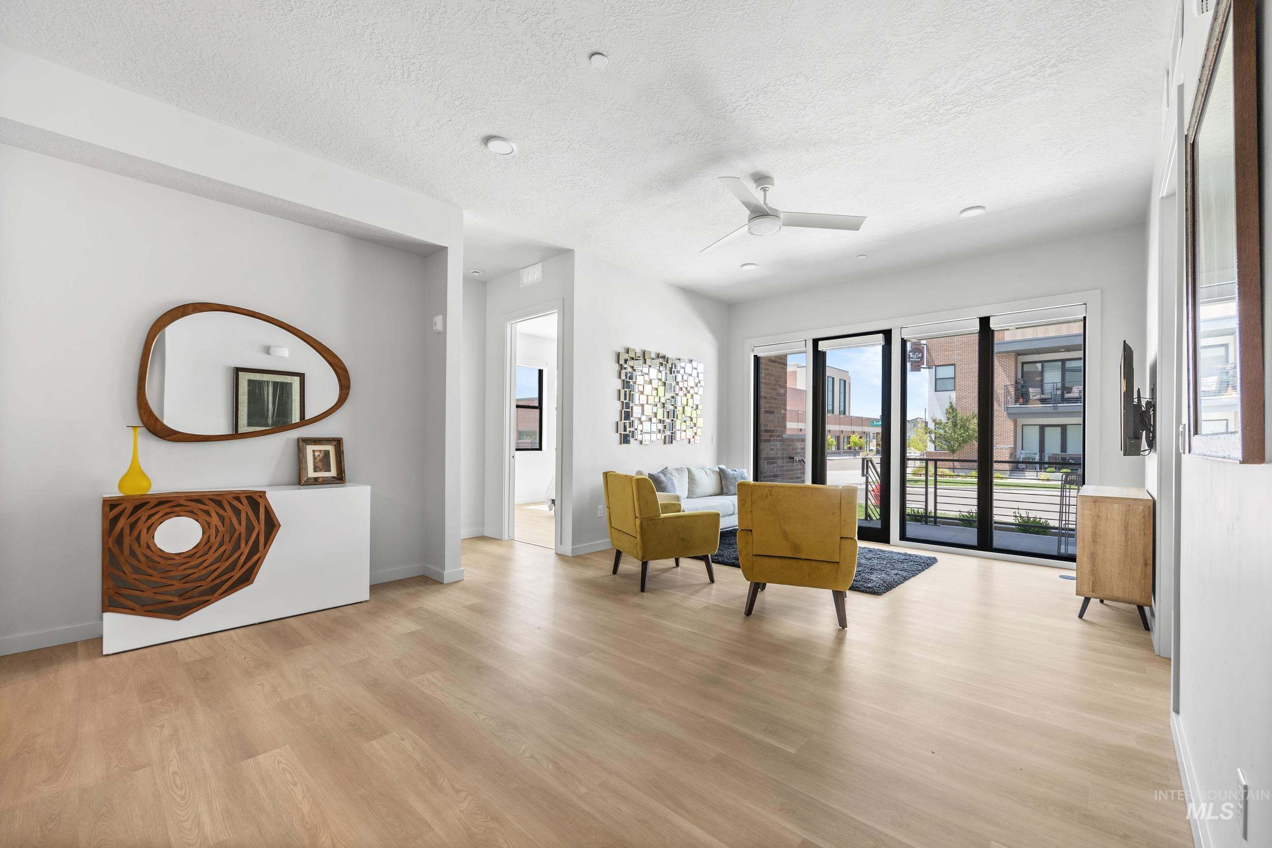 Sitting room featuring light wood-style floors, a textured ceiling, and a ceiling fan