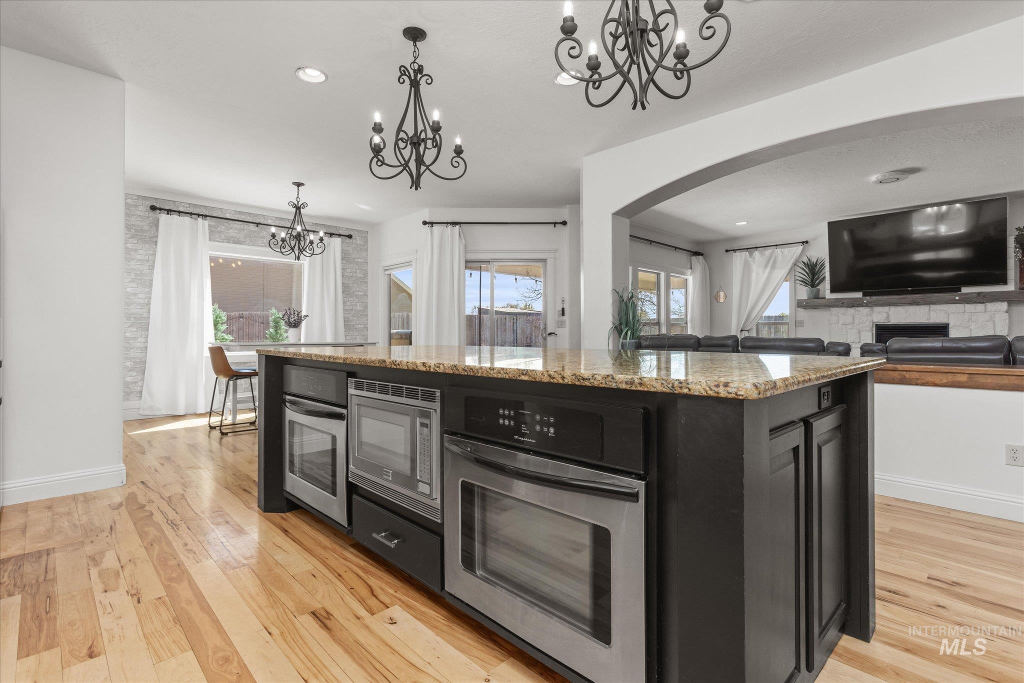 Kitchen island featuring a granite-style countertop, built-in stainless steel appliances, and dark cabinetry