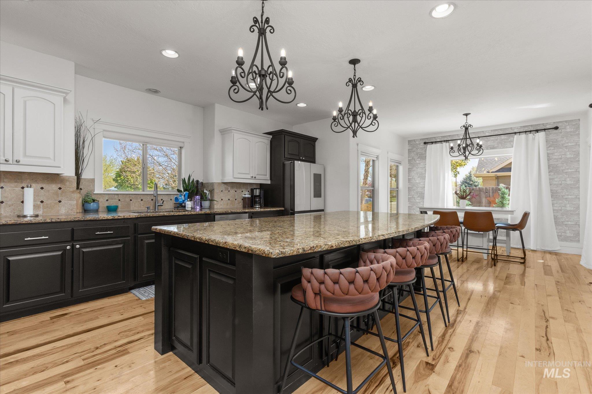 Spacious kitchen featuring a large central island with seating, recessed lighting, and elegant chandeliers