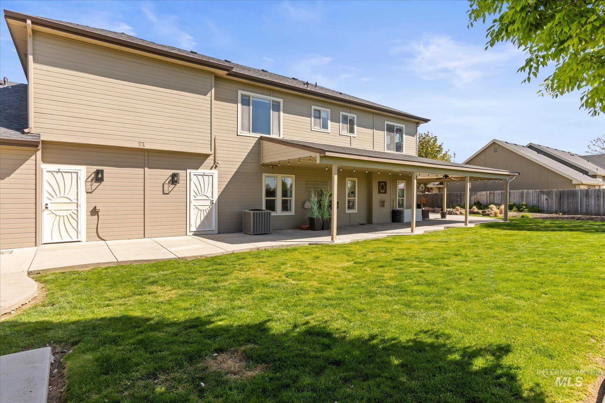 Expansive backyard featuring a manicured lawn and a covered patio