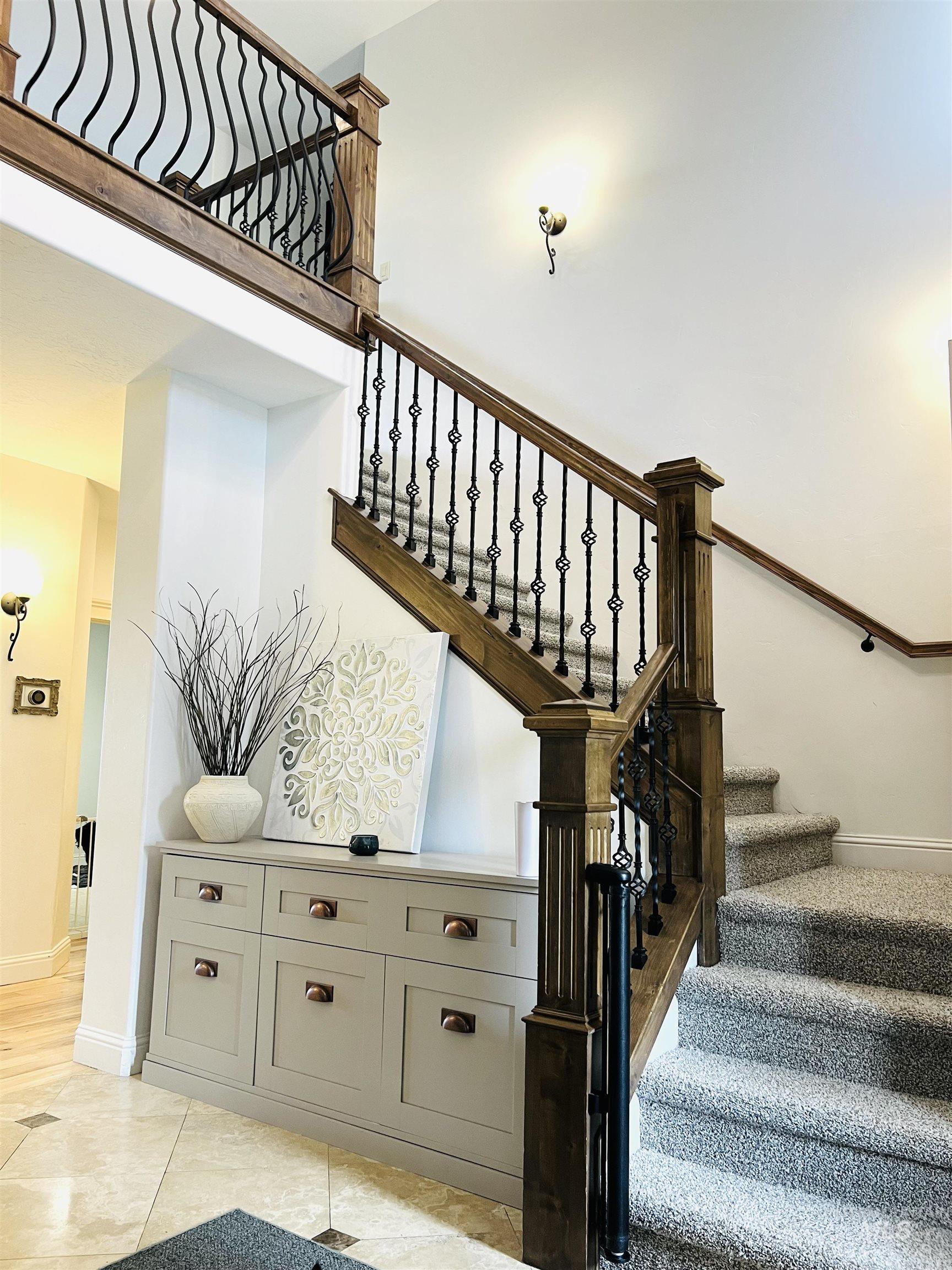Two-story entryway featuring a grand staircase with wrought iron balusters and wood handrails