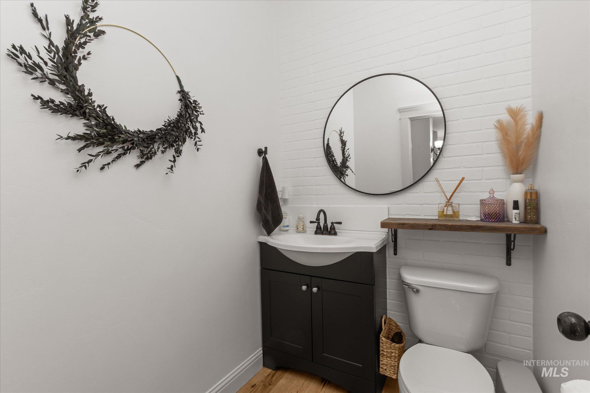 Compact powder room featuring a dark vanity with integrated sink, a circular mirror, and white brick-patterned wall tiling