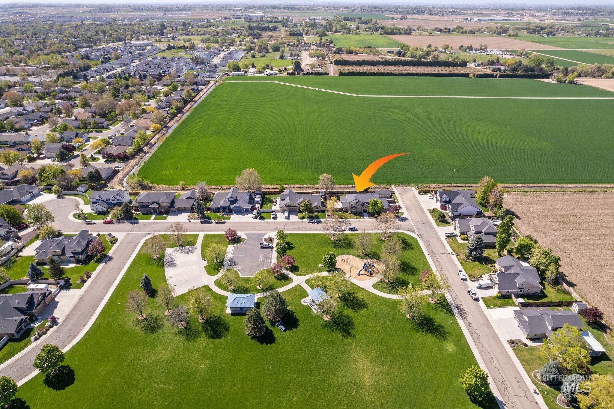 Aerial perspective showcasing the residential neighborhood bordering expansive green fields