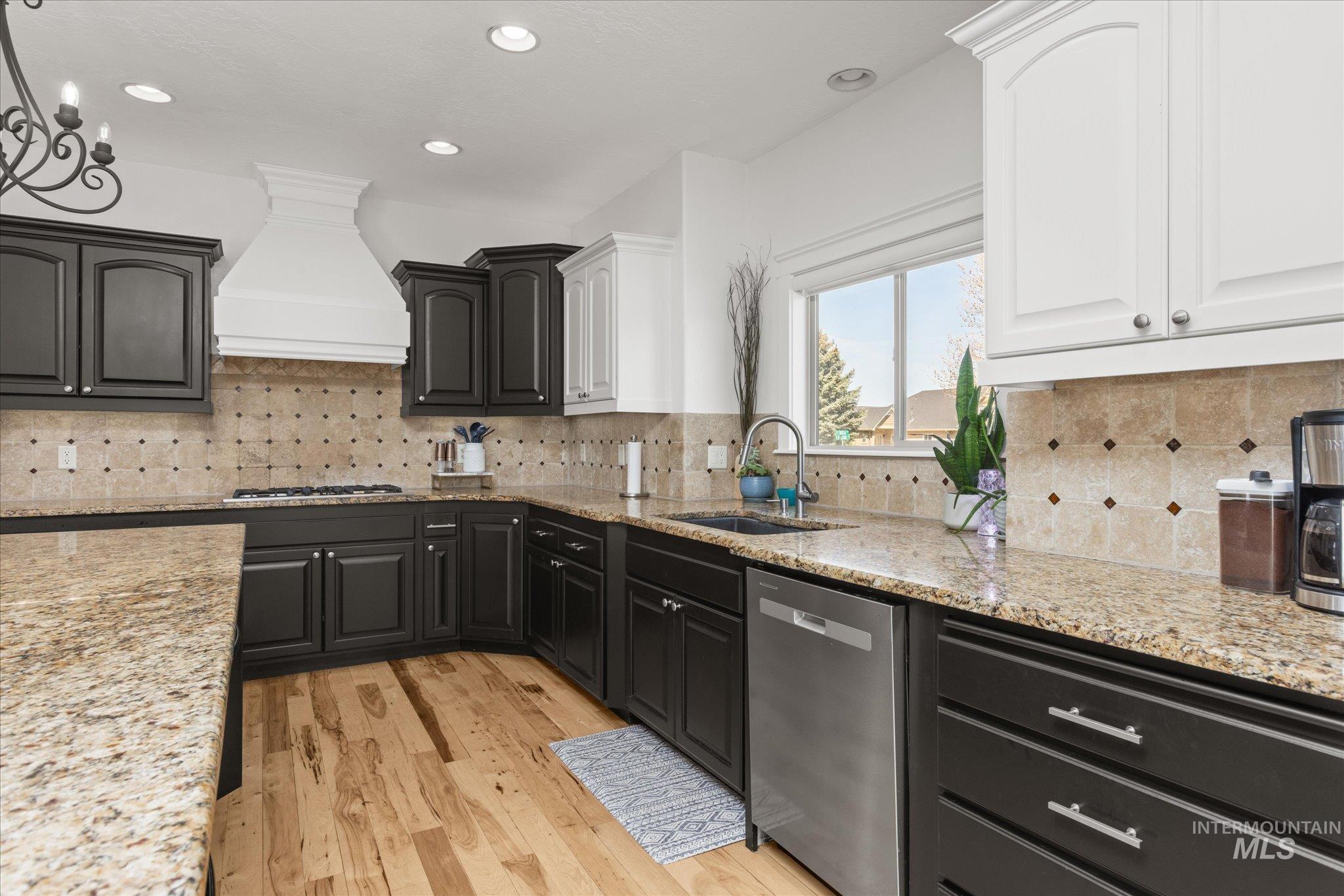 Kitchen featuring wood-finish flooring, dark lower cabinetry, and light upper cabinetry