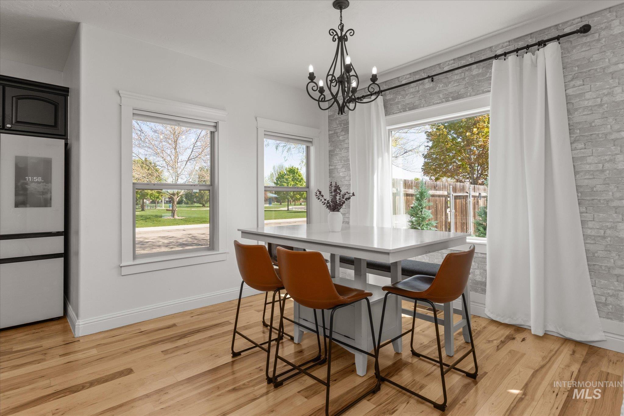 Dining area featuring wood-finish flooring, white walls, and a light gray brick accent wall