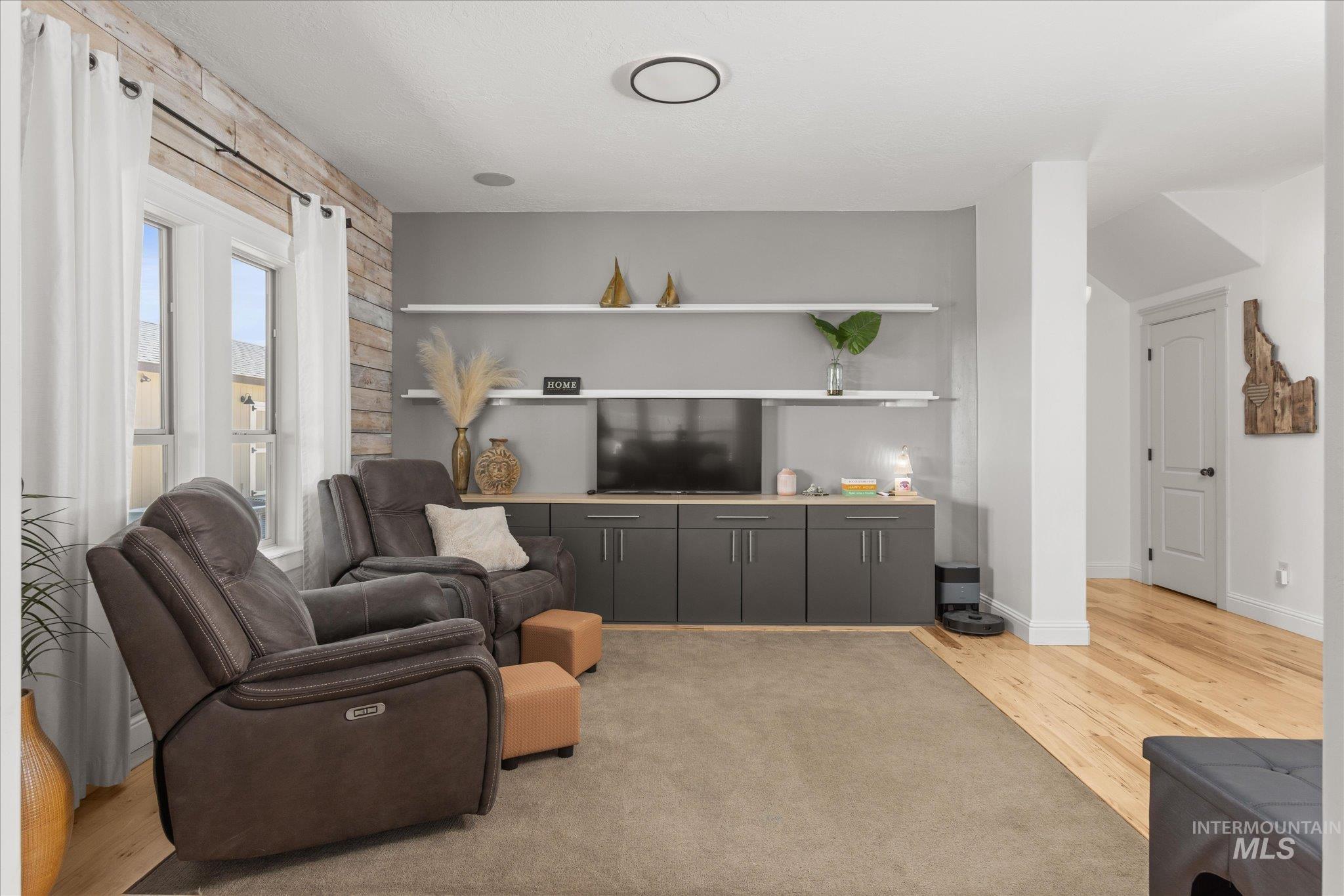 Spacious living area featuring a wood-panel accent wall, built-in shelving, and a media console with cabinetry