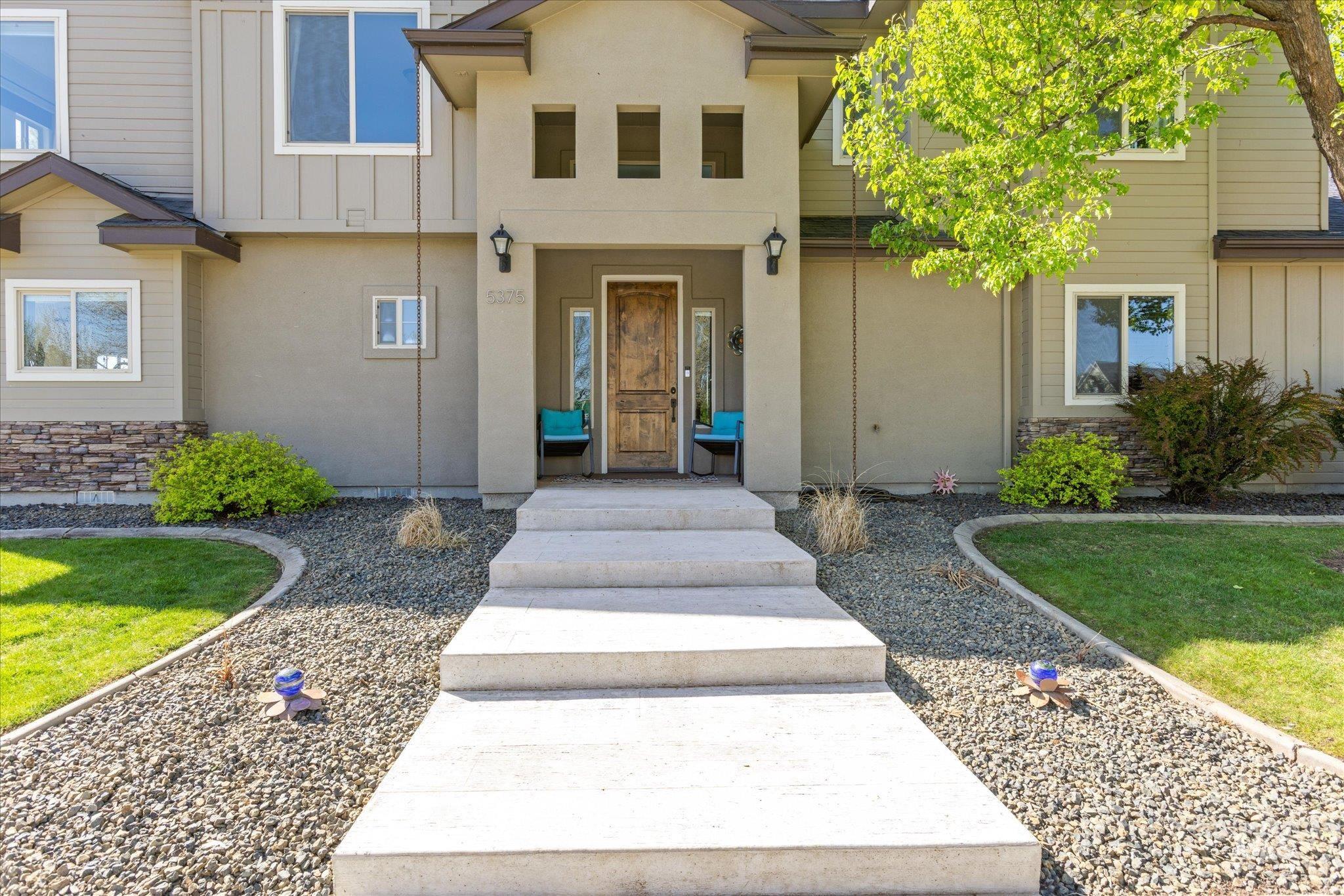 Contemporary exterior featuring a panel-paneled entry door, stacked stone accents, and a covered porch