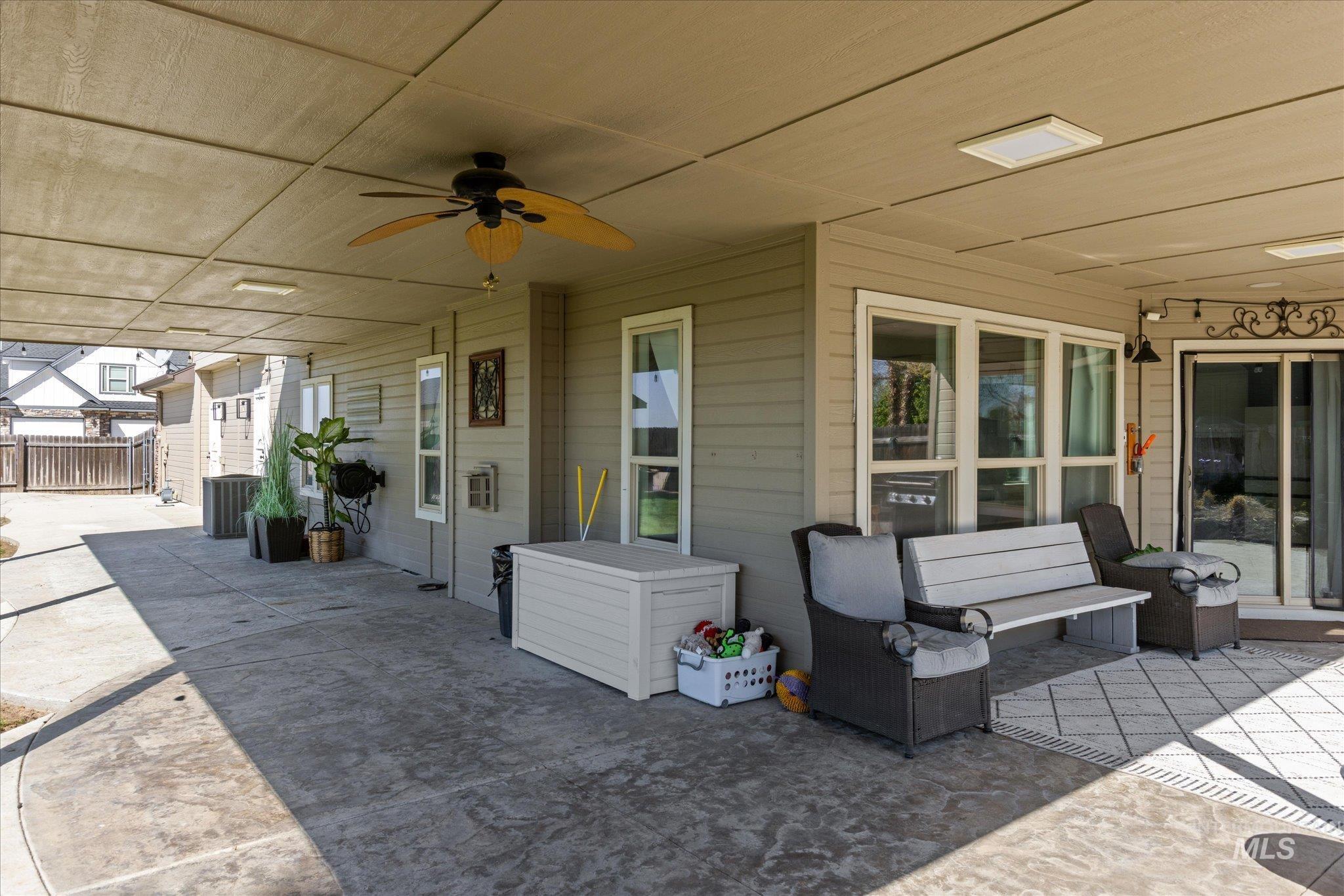 Expansive covered patio featuring stamped concrete flooring, a ceiling fan, recessed lighting, and multiple windows