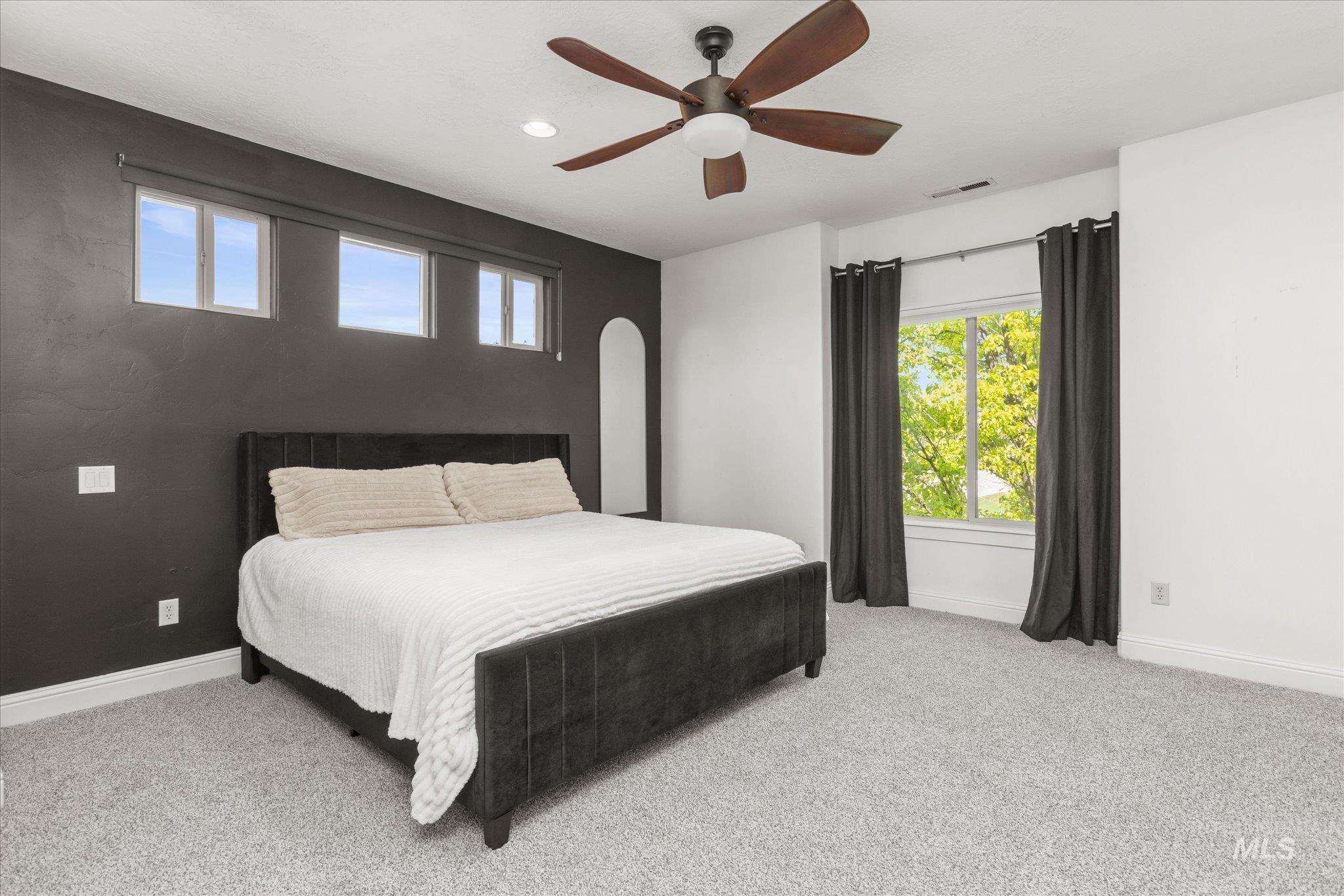 Spacious room featuring light gray carpeting and a prominent dark accent wall