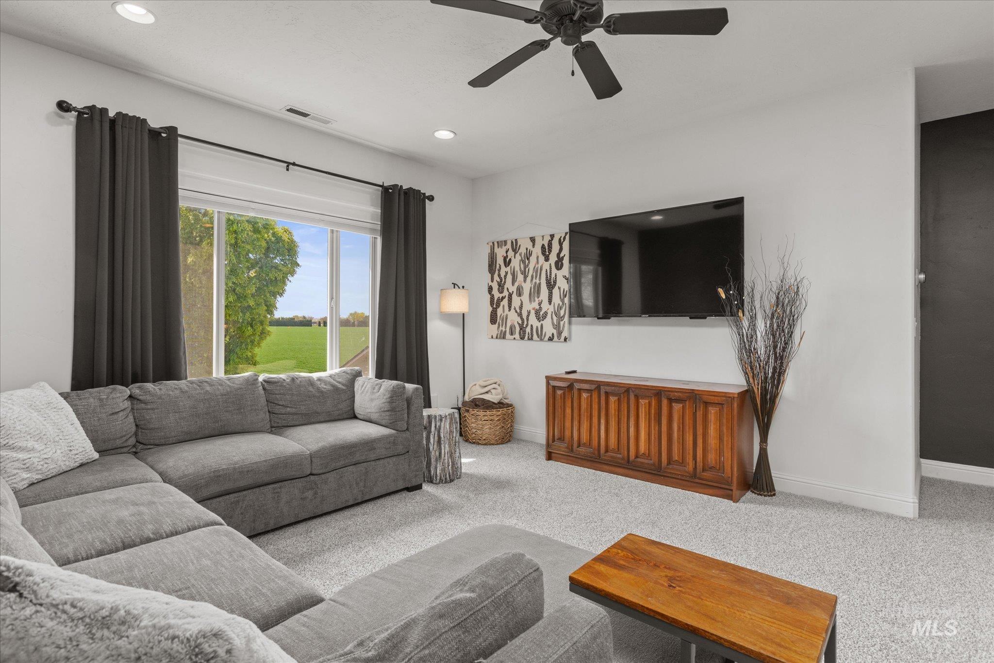 Spacious living area featuring light gray carpeting, recessed lighting, and a ceiling fan