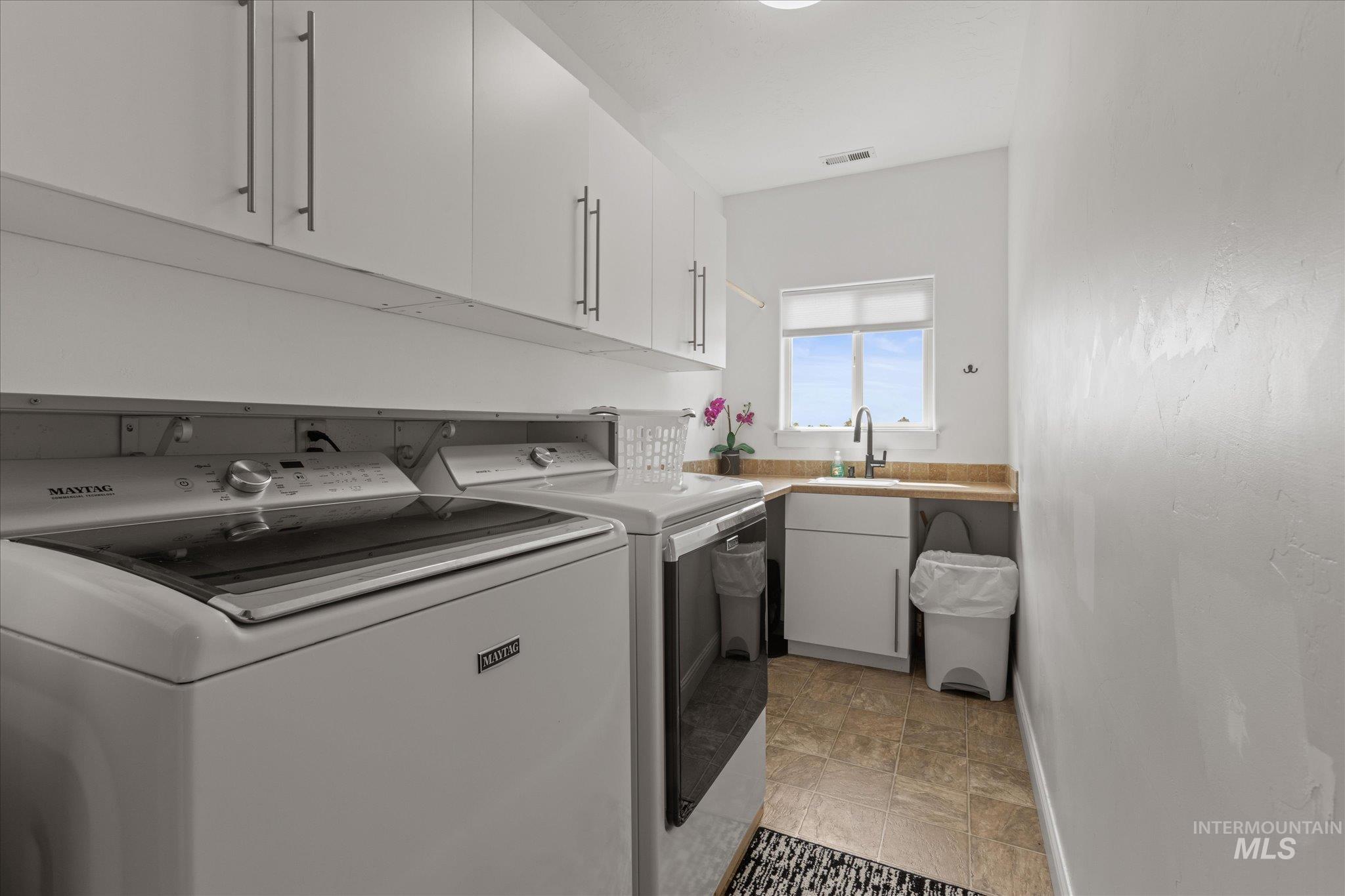 Laundry space featuring extensive white cabinetry, a utility sink with a window, and wood-finish countertops