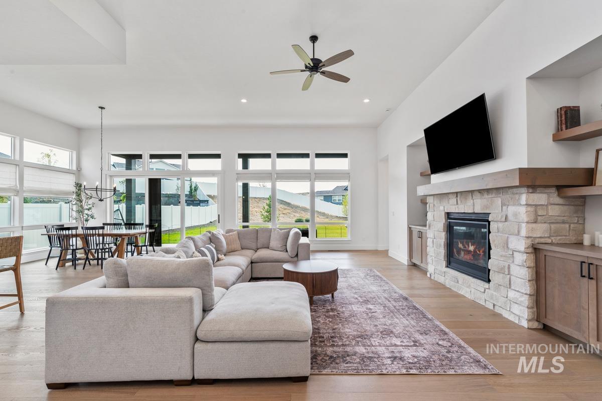 Living area featuring light wood finished floors, healthy amount of natural light, a stone fireplace, recessed lighting, and a ceiling fan