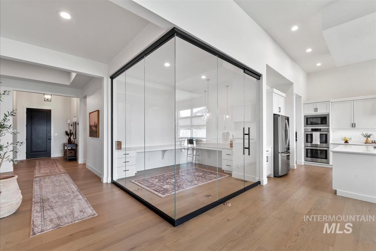 Living area with light wood-style flooring, recessed lighting, and a desk