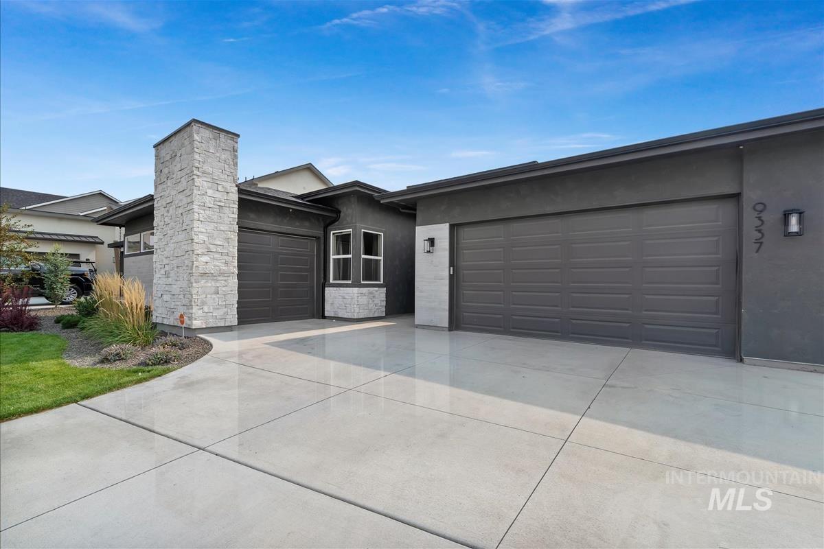 Ranch-style house with stucco siding, driveway, a garage, and stone siding