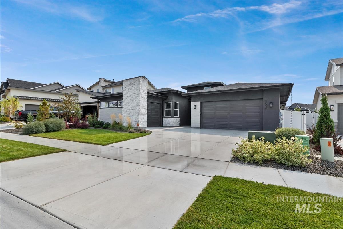 View of front facade with driveway, an attached garage, stone siding, stucco siding, and a front yard