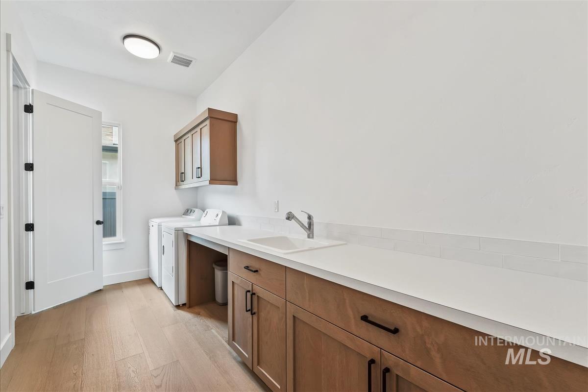 Washroom featuring light wood-type flooring, cabinet space, and independent washer and dryer