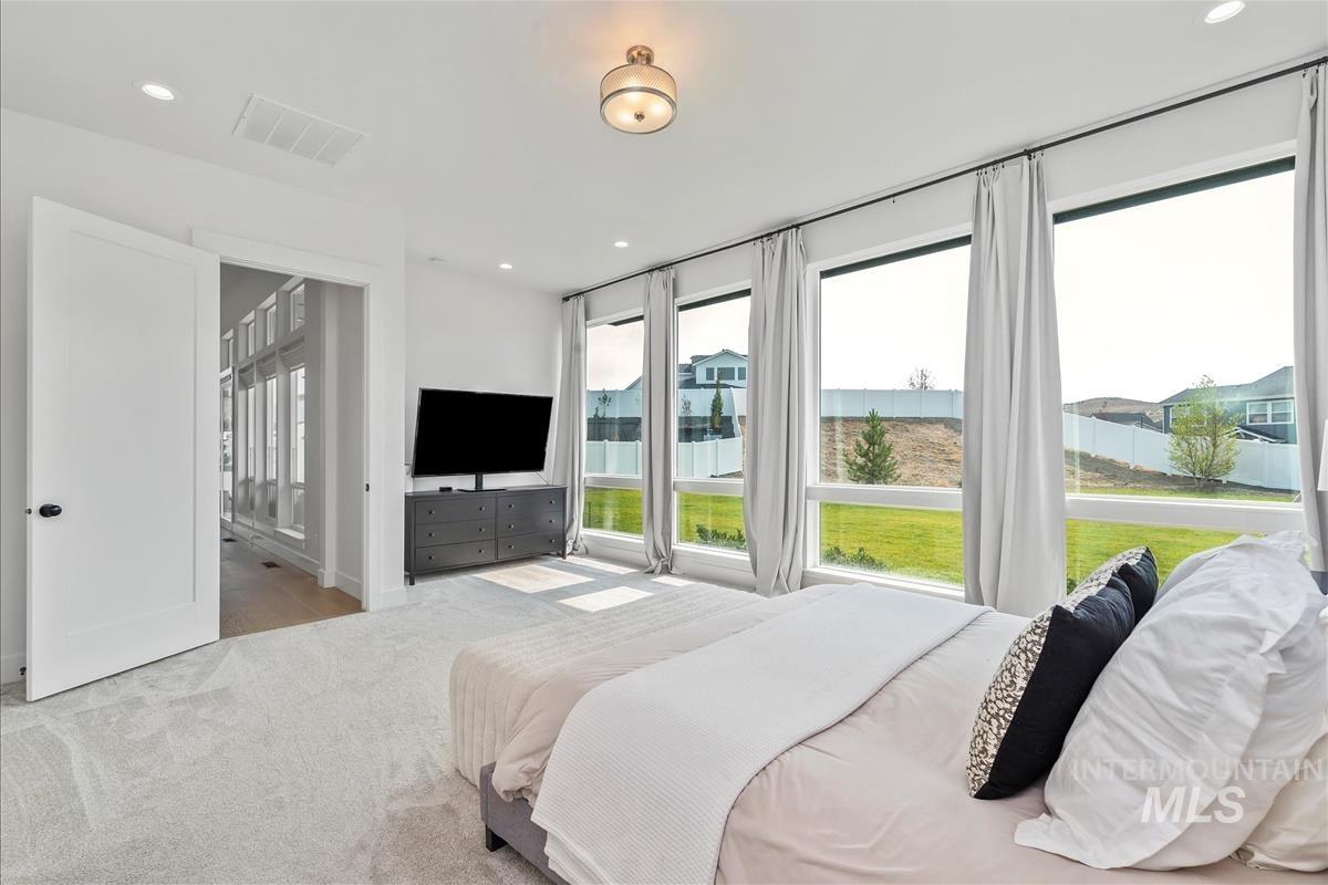 Carpeted bedroom with multiple windows and recessed lighting