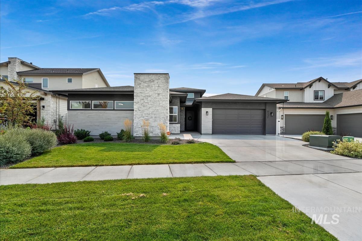 View of front of house with driveway, stone siding, an attached garage, a front lawn, and stucco siding
