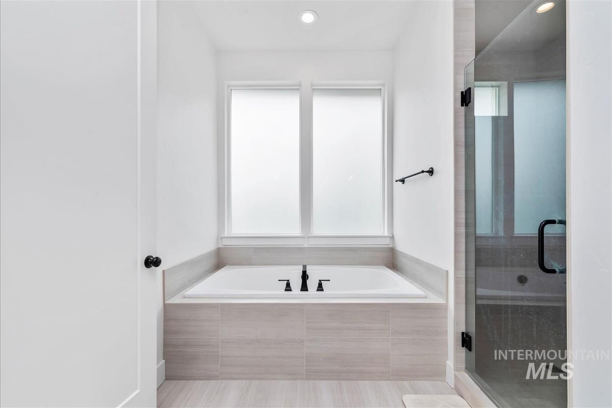 Full bath with healthy amount of natural light, a garden tub, a stall shower, and recessed lighting