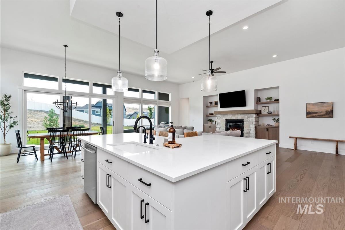 Kitchen featuring white cabinets, a stone fireplace, ceiling fan, recessed lighting, and open floor plan