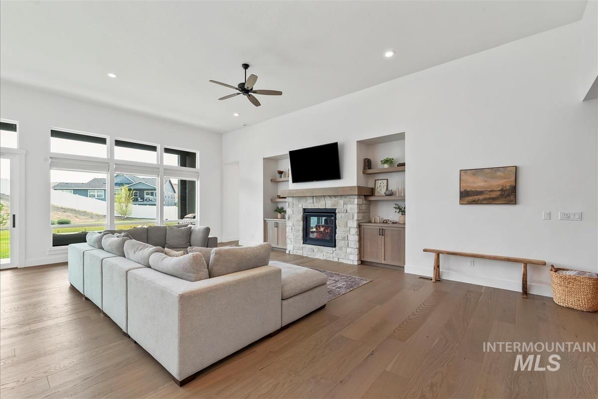 Living area featuring built in shelves, a fireplace, recessed lighting, wood finished floors, and ceiling fan