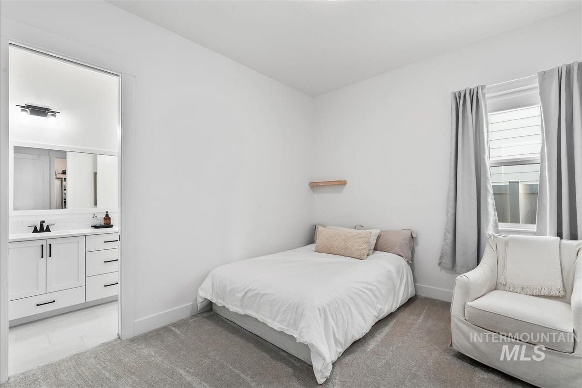 Bedroom featuring light carpet and ensuite bathroom