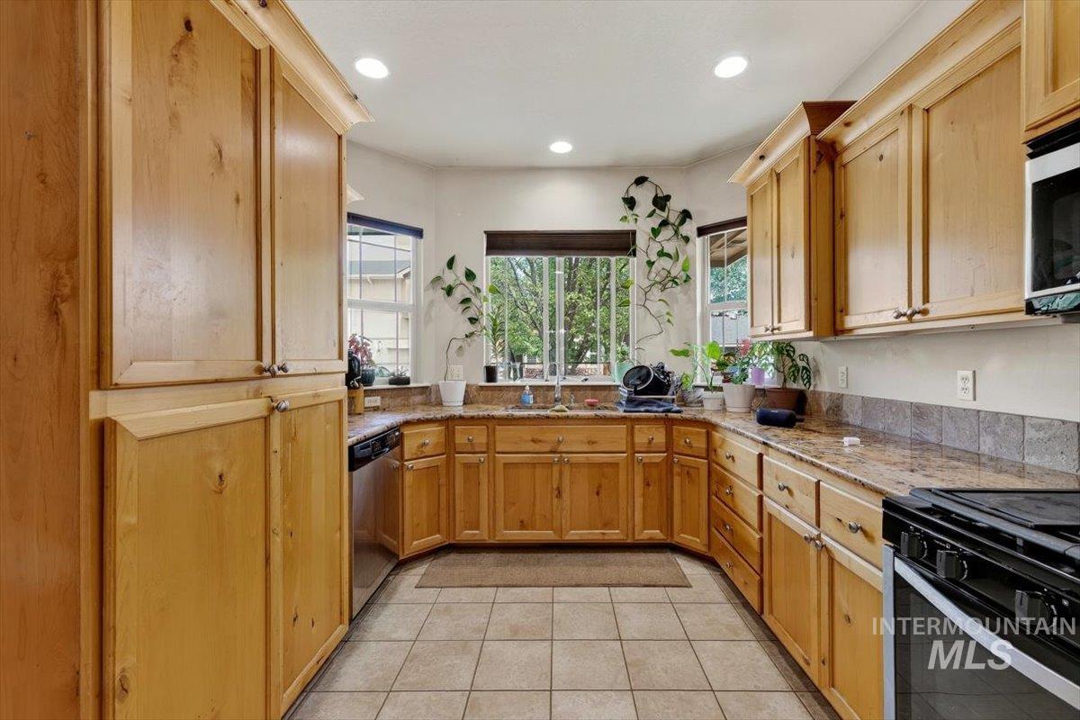 Kitchen featuring U-shaped cabinetry with natural wood-finish, stone countertops, and a tile backsplash