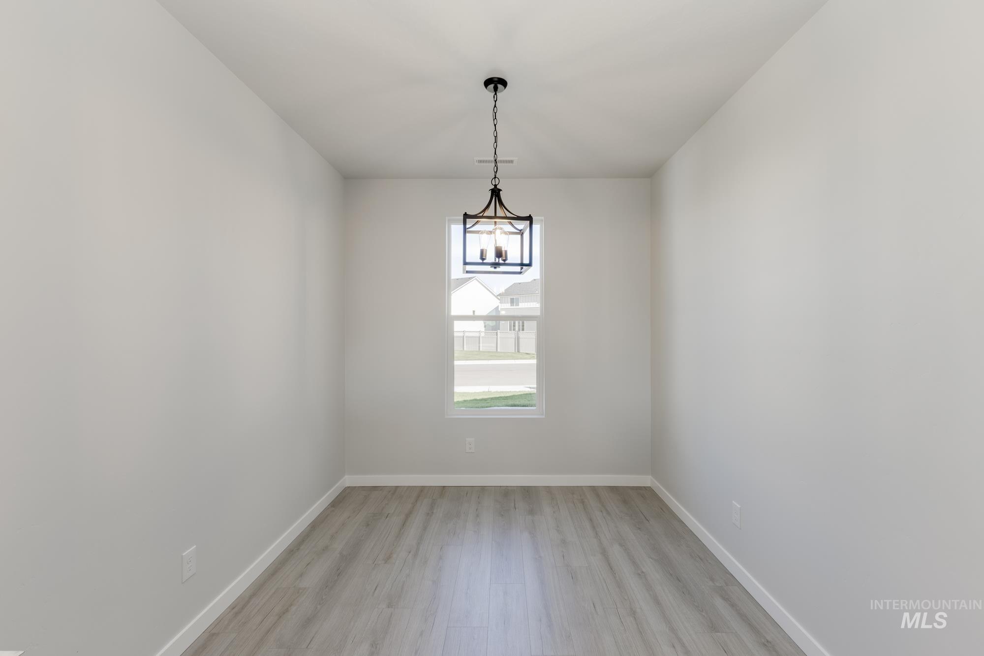 Spare room with light wood-style floors and a chandelier