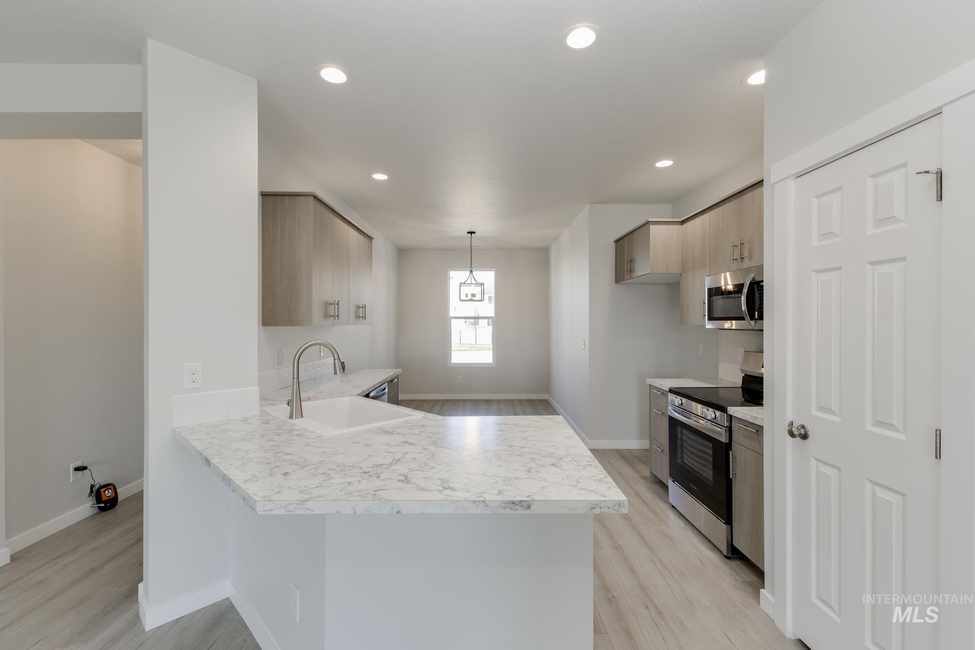 Kitchen with light countertops, stainless steel appliances, a peninsula, light wood-style flooring, and recessed lighting