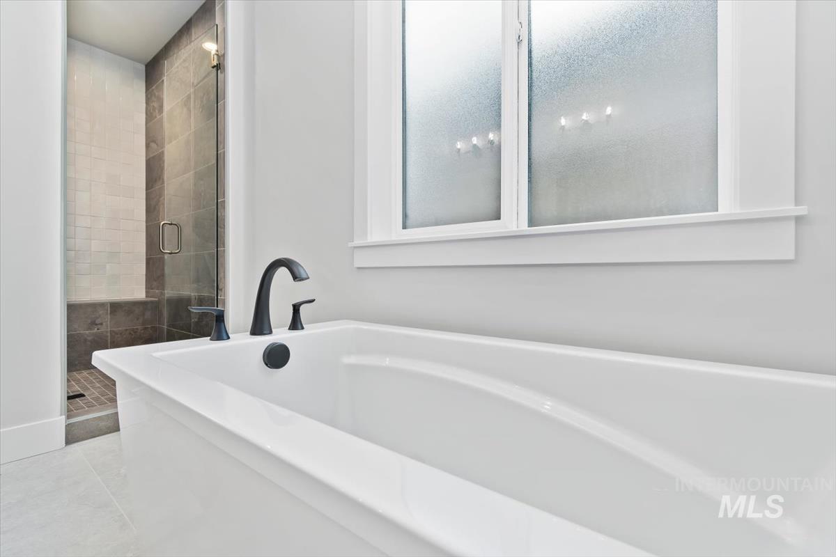 Full bathroom featuring a soaking tub, a stall shower, and light tile patterned flooring