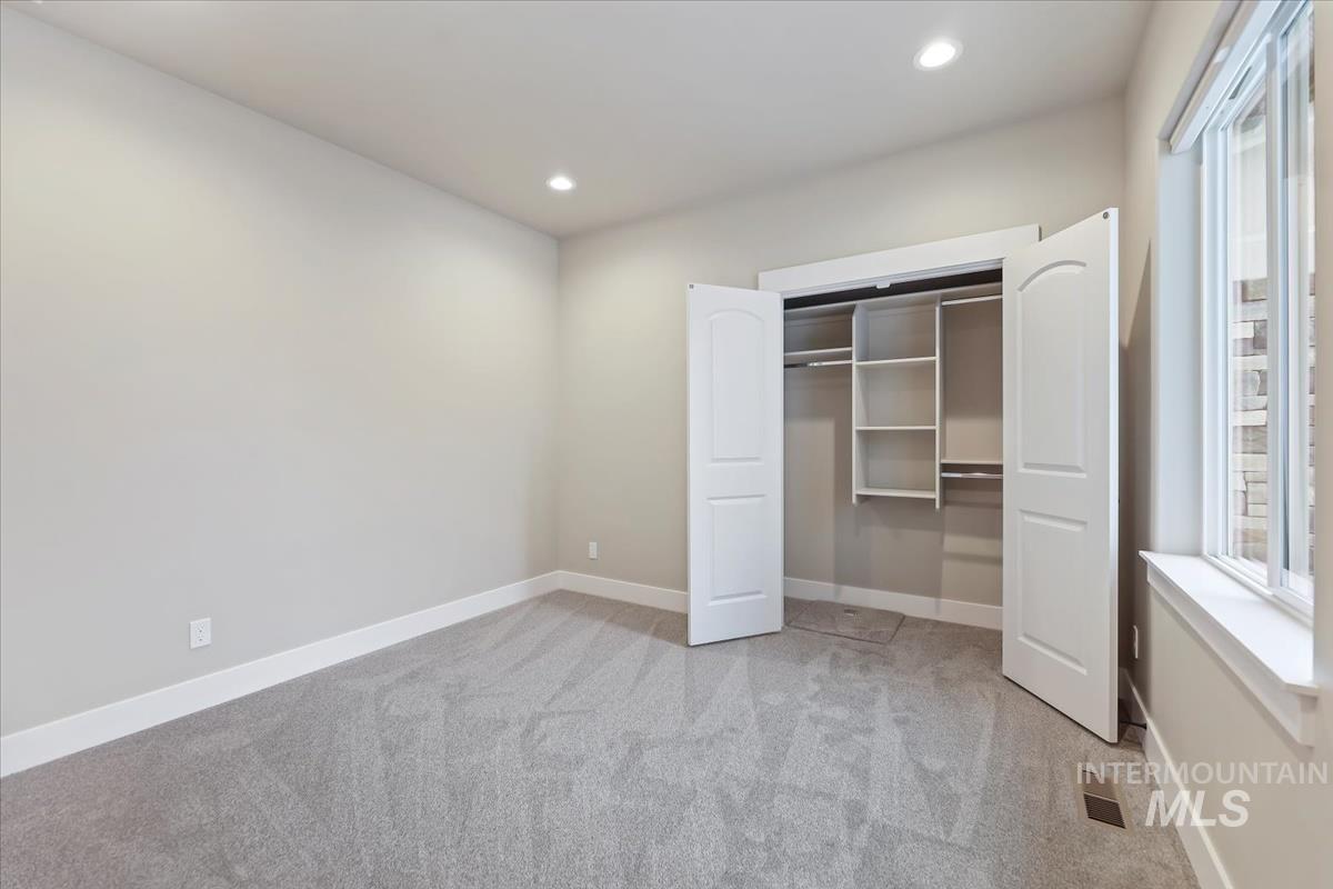 Unfurnished bedroom featuring light colored carpet, recessed lighting, and a closet