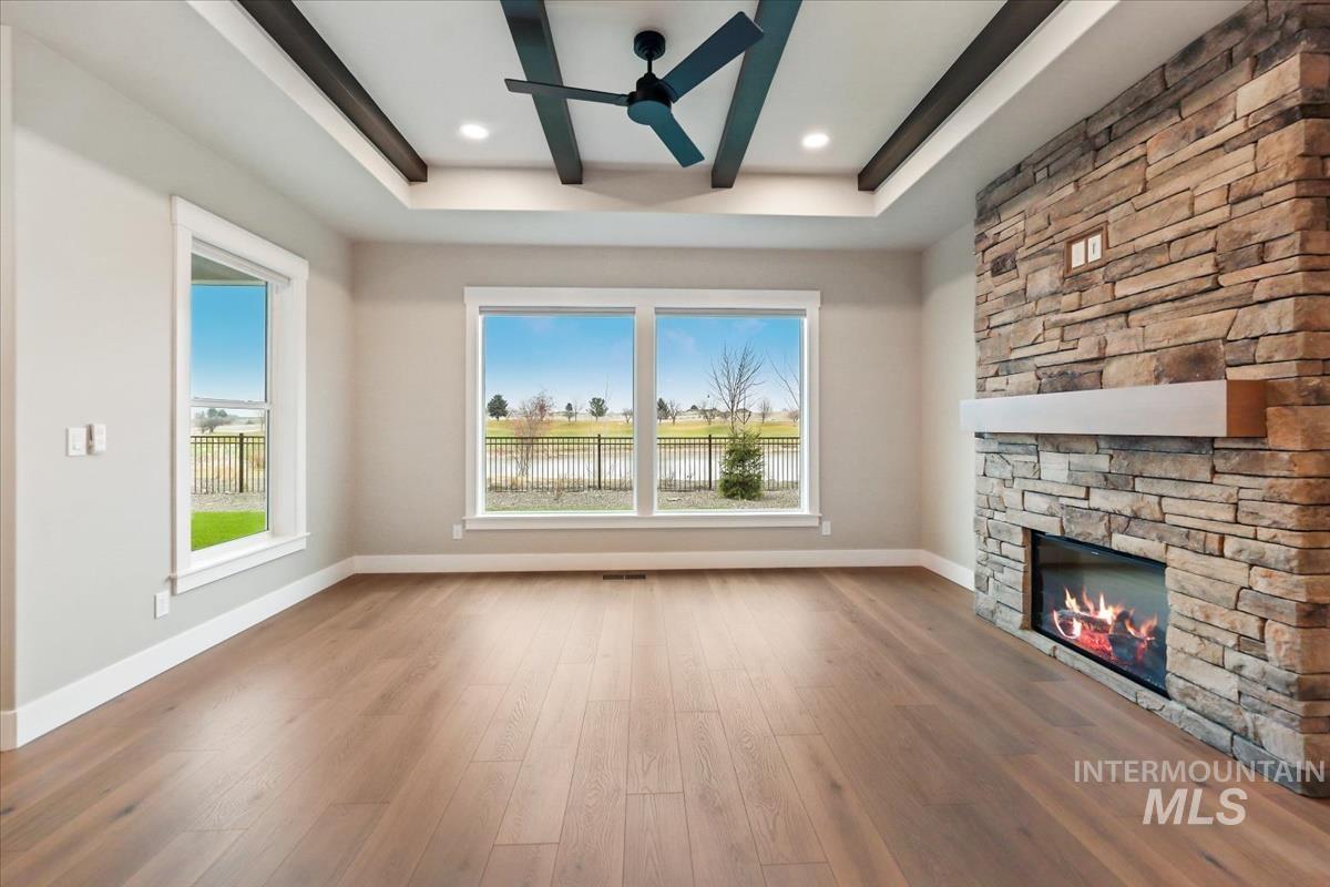Unfurnished living room featuring a fireplace, wood finished floors, ceiling fan, and plenty of natural light