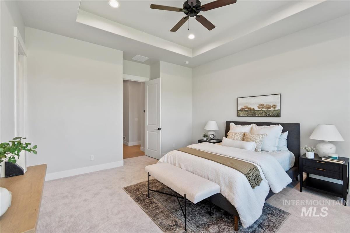 Bedroom featuring a raised ceiling, light colored carpet, recessed lighting, and ceiling fan