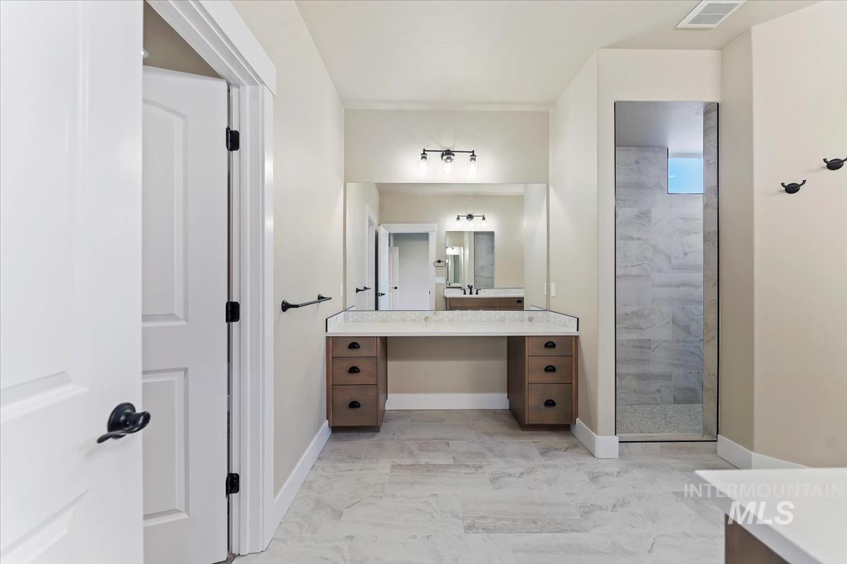 Bathroom with vanity, light marble finish floors, and a stall shower