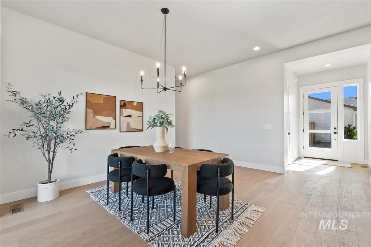 Dining room with light wood finished floors, a chandelier, and recessed lighting
