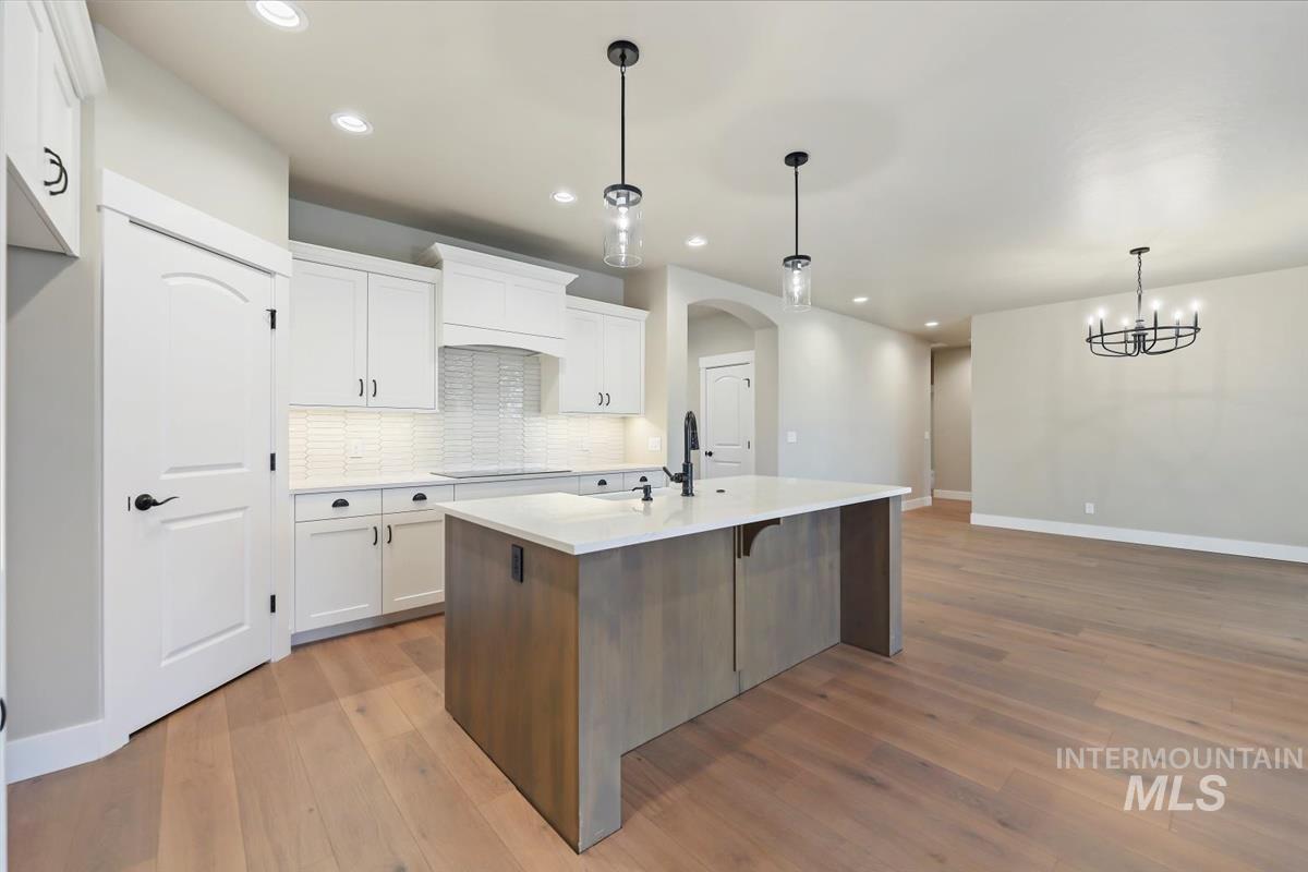 Kitchen featuring white cabinetry, a breakfast bar area, arched walkways, dark wood-type flooring, and pendant lighting
