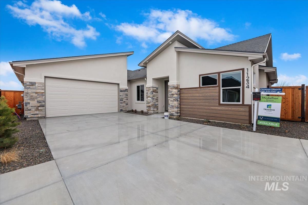 Contemporary house with stucco siding, stone siding, driveway, and a garage