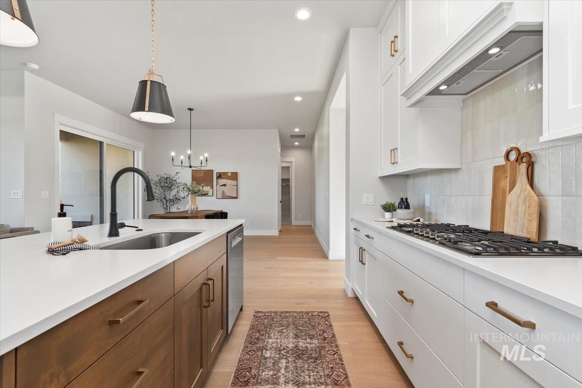 Kitchen with white cabinets, recessed lighting, custom exhaust hood, pendant lighting, and light wood finished floors