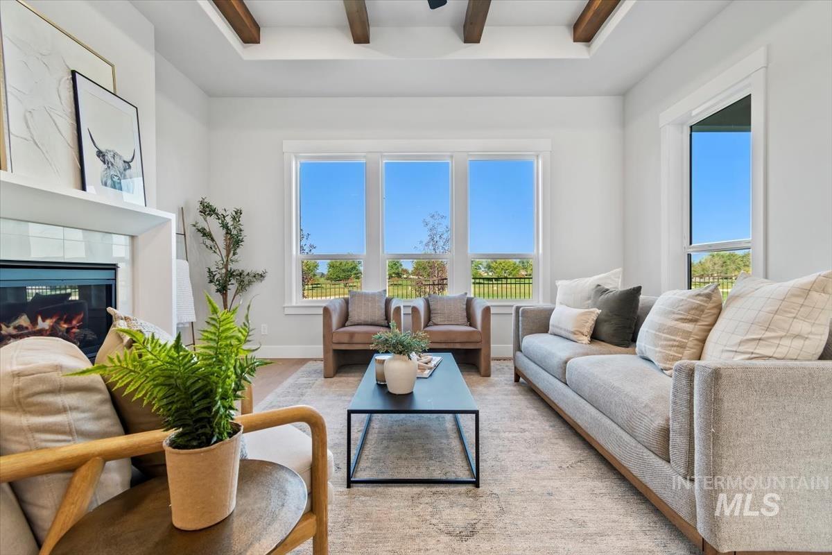 Living room with a tiled fireplace, beam ceiling, and healthy amount of natural light
