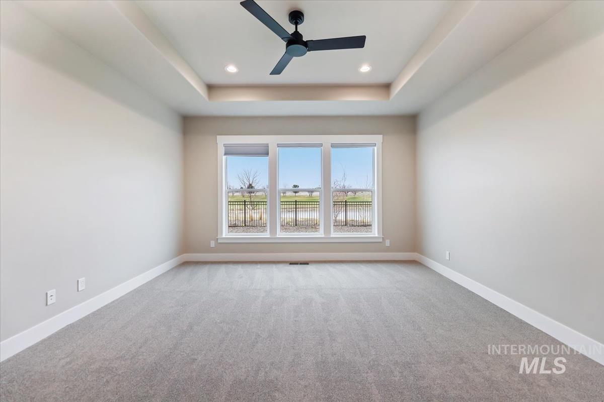 Unfurnished room featuring light carpet, ceiling fan, a raised ceiling, and recessed lighting