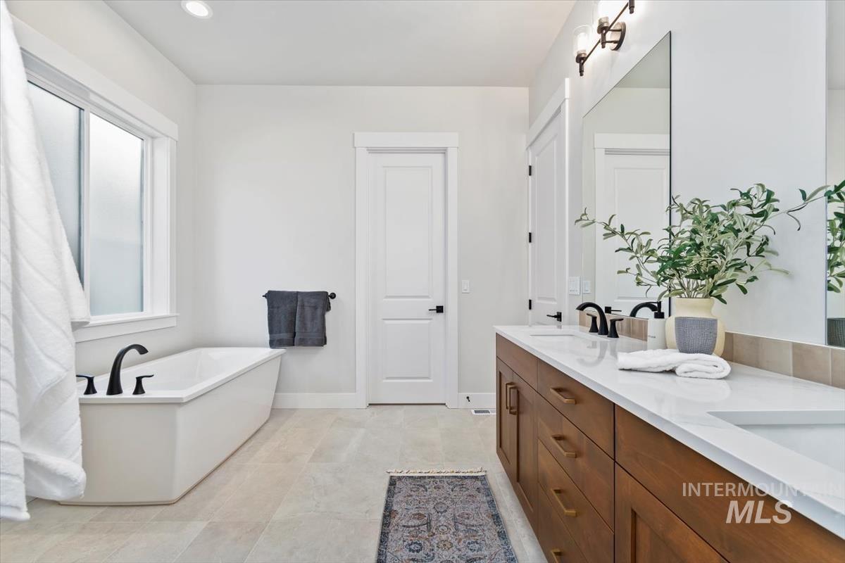 Full bath with double vanity, a soaking tub, and recessed lighting