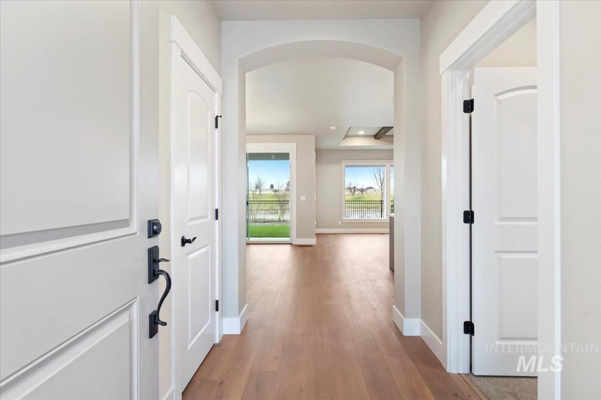 Hallway with arched walkways, light wood-style floors, and recessed lighting
