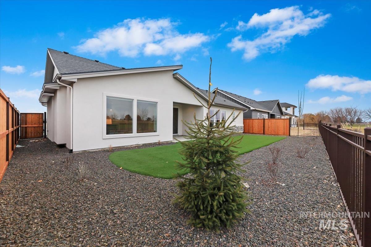 Back of property featuring a fenced backyard, stucco siding, and roof with shingles