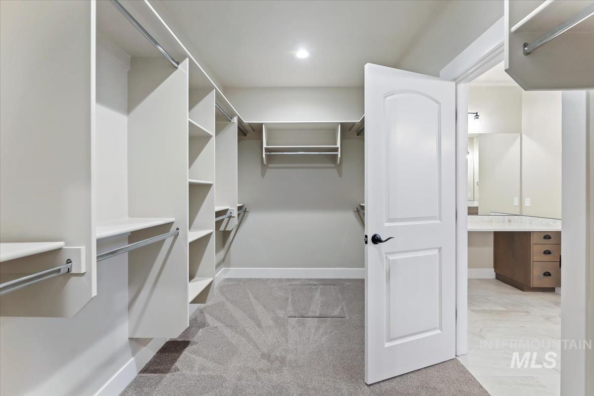 Walk in closet featuring light colored carpet