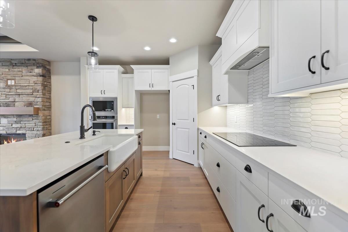 Kitchen featuring white cabinetry, stainless steel appliances, light wood-style floors, a kitchen island with sink, and recessed lighting