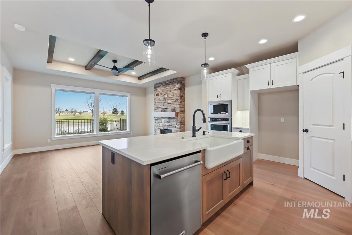 Kitchen featuring stainless steel appliances, open floor plan, light wood finished floors, hanging light fixtures, and recessed lighting