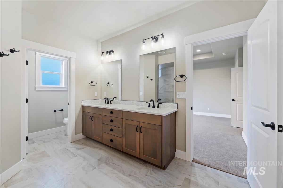 Full bath featuring light marble finish flooring and double vanity